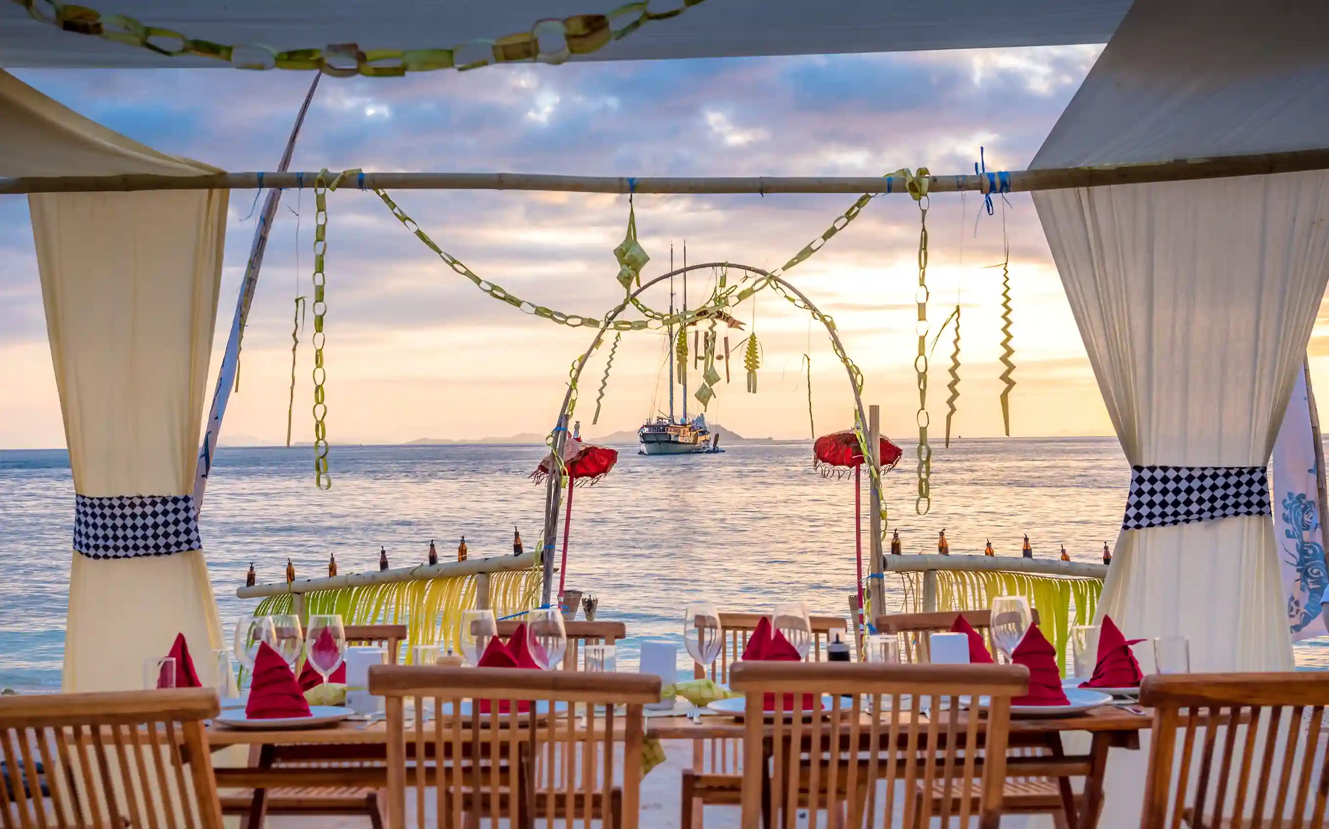 Table set on the beach at sunset with a boat on the horizon