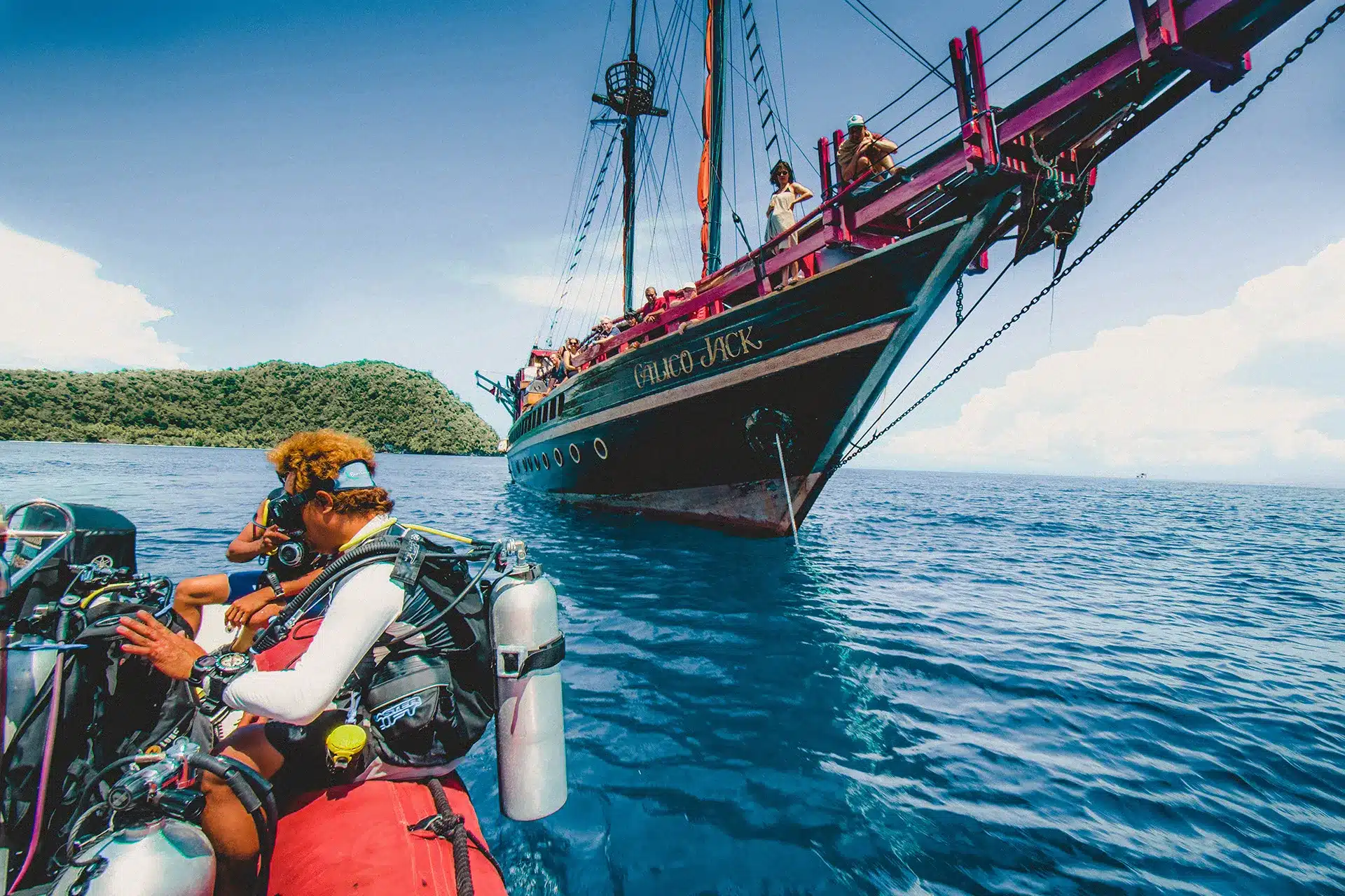 Diver kitting up on the tender with the dive boat behind