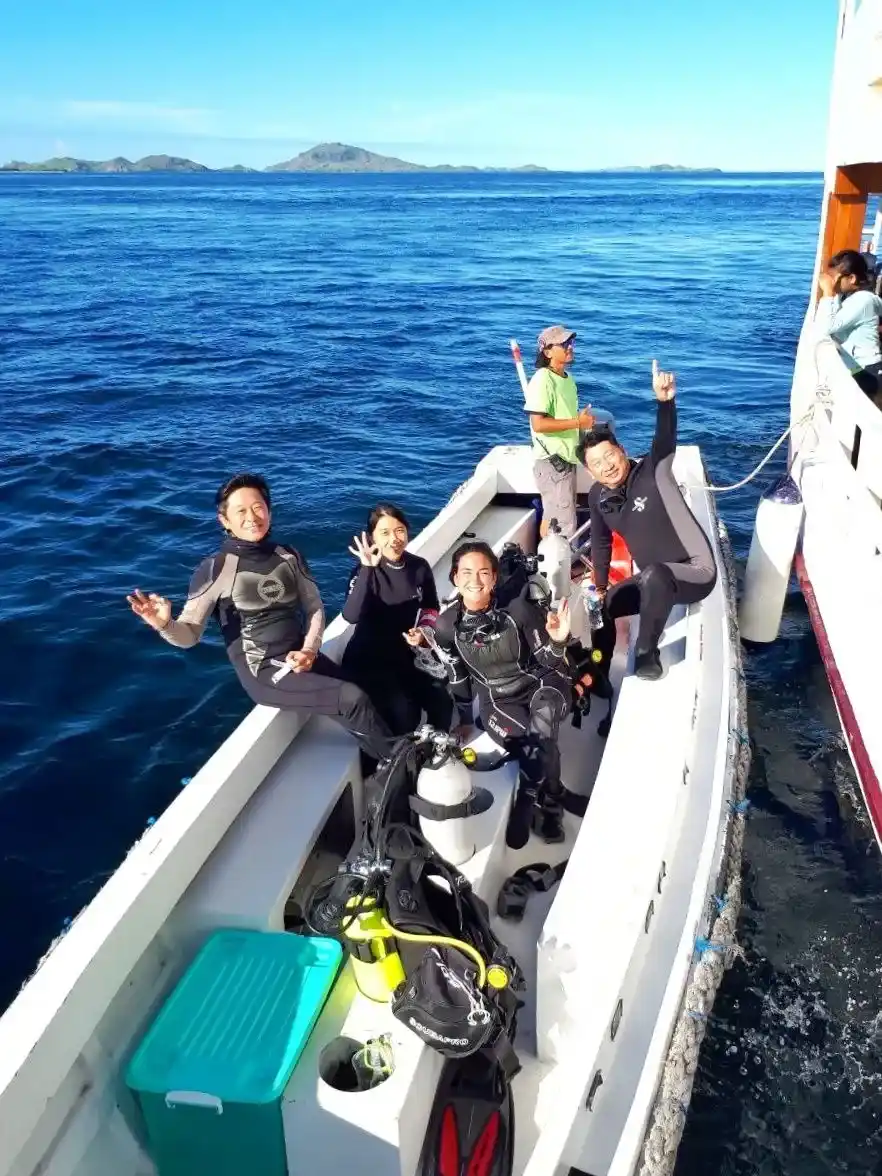 Divers in full gear on the tender, arms up after a dive