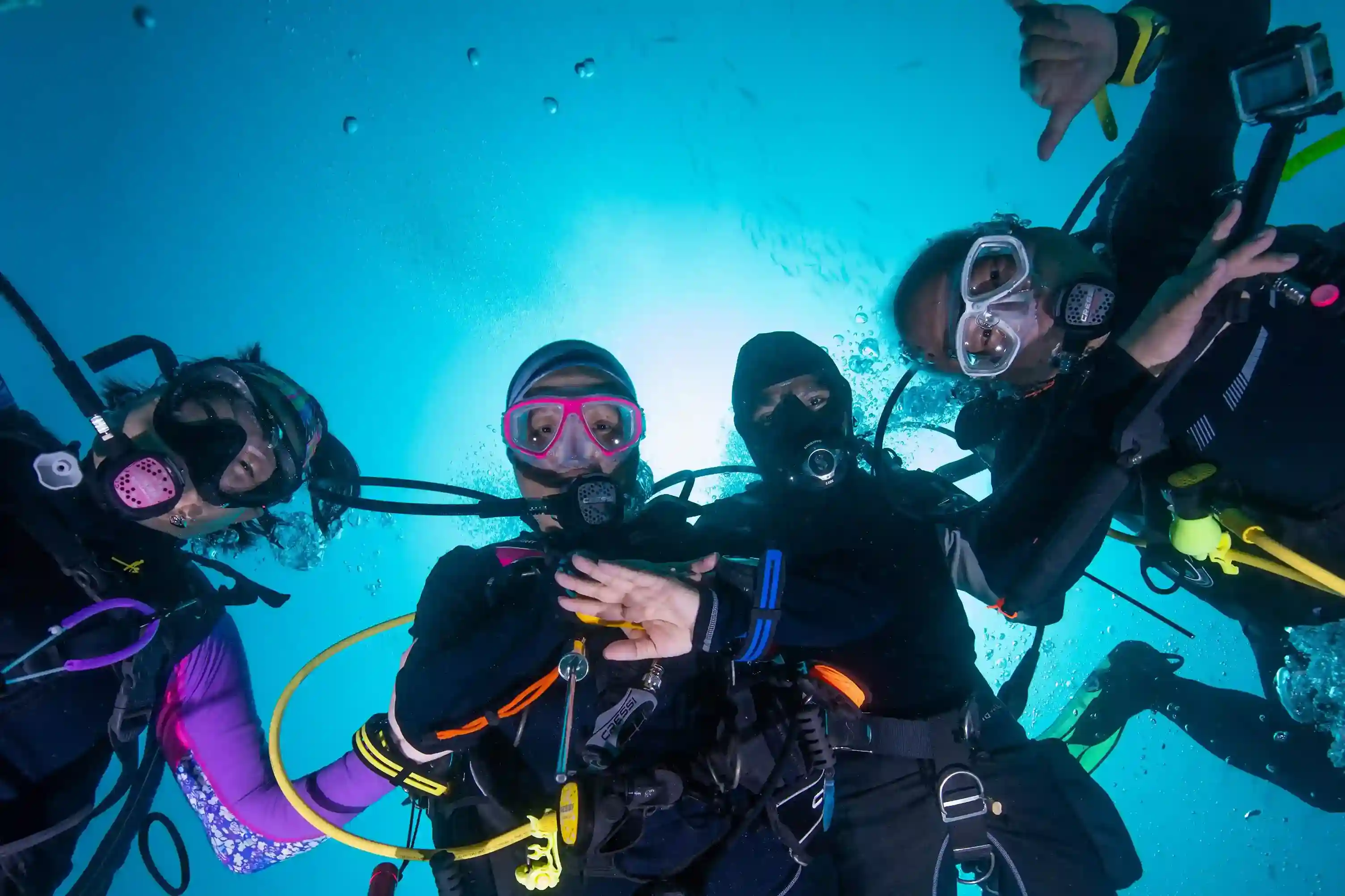 Group of divers underwater together with the sun behind them