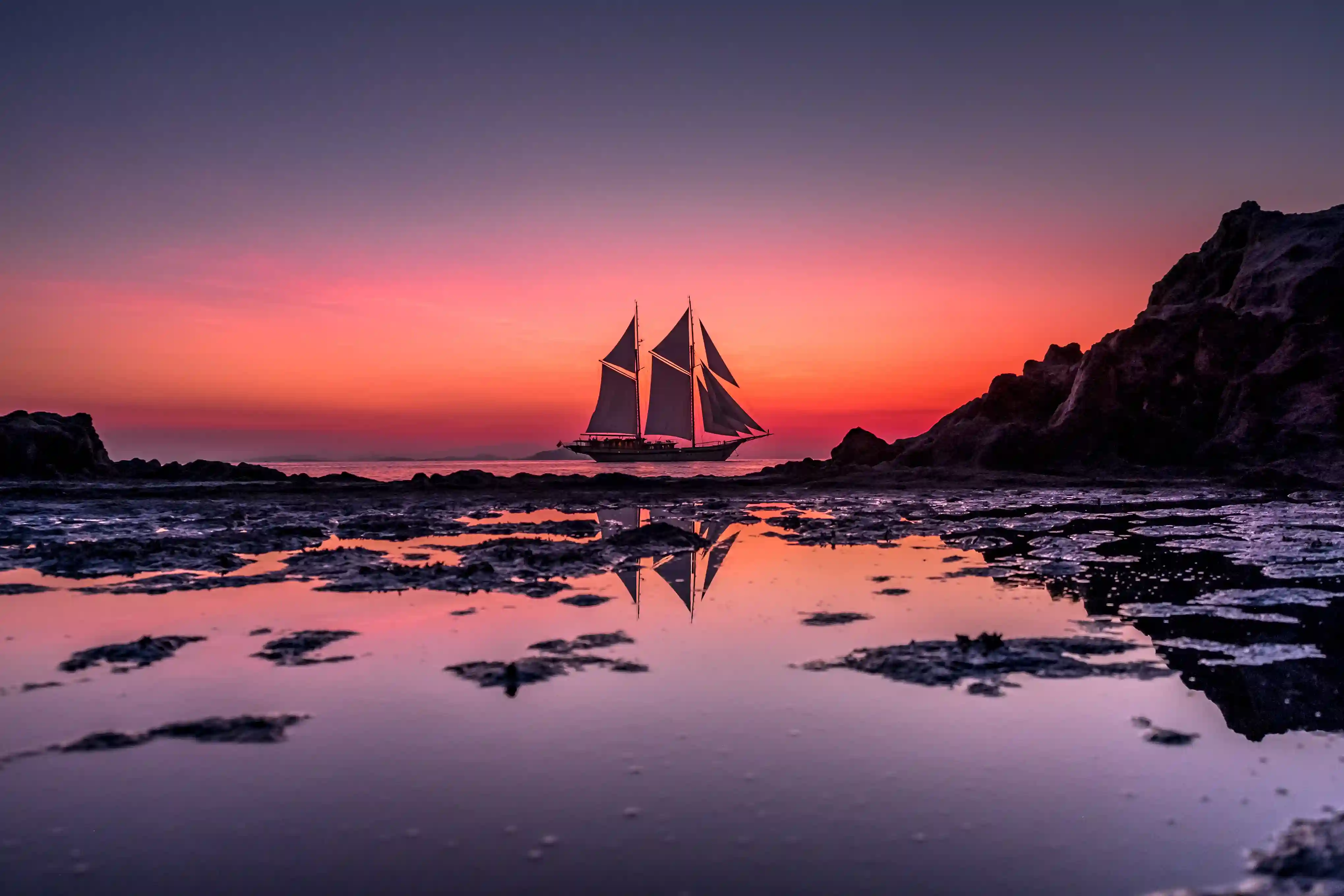 Sailing boat silhouetted against a magenta twilight sky